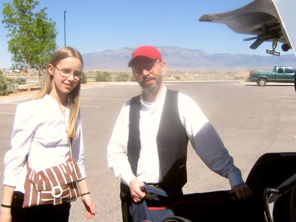 Two musicians from the Ensemble M’chaiya (tm) unloading equipment from a car’s trunk. The Sandia Mountains are in the background. © 2010 Modal Music, Inc. (tm) All rights reserved.